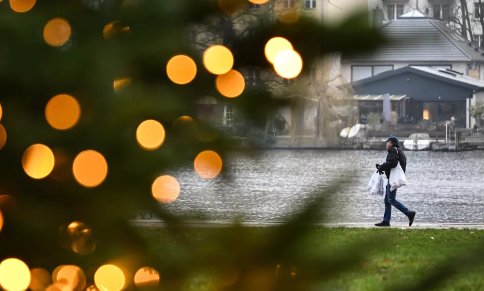 PRODUCTION - 22 December 2025, Berlin: A young man carrying shopping bags walks along the banks of the Mueggelspree in the old town of Koepenick. Photo: Britta Pedersen/dpa / Foto: Britta Pedersen