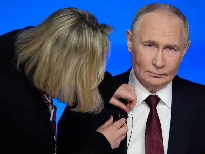 A TV assistant attaches a microphone to Russian President Vladimir Putin's suit prior to his annual news conference and call-in show at Gostinny Dvor, in Moscow, on Friday, Dec. 19, 2025. (AP Photo/Pavel Bednyakov)