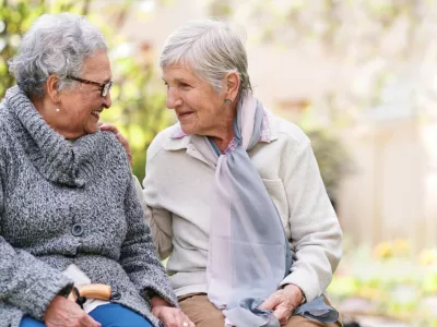 Two elderly women sitting on bench in park smiling happy life long friends enjoying retirement / Foto: Jacob Wackerhausen