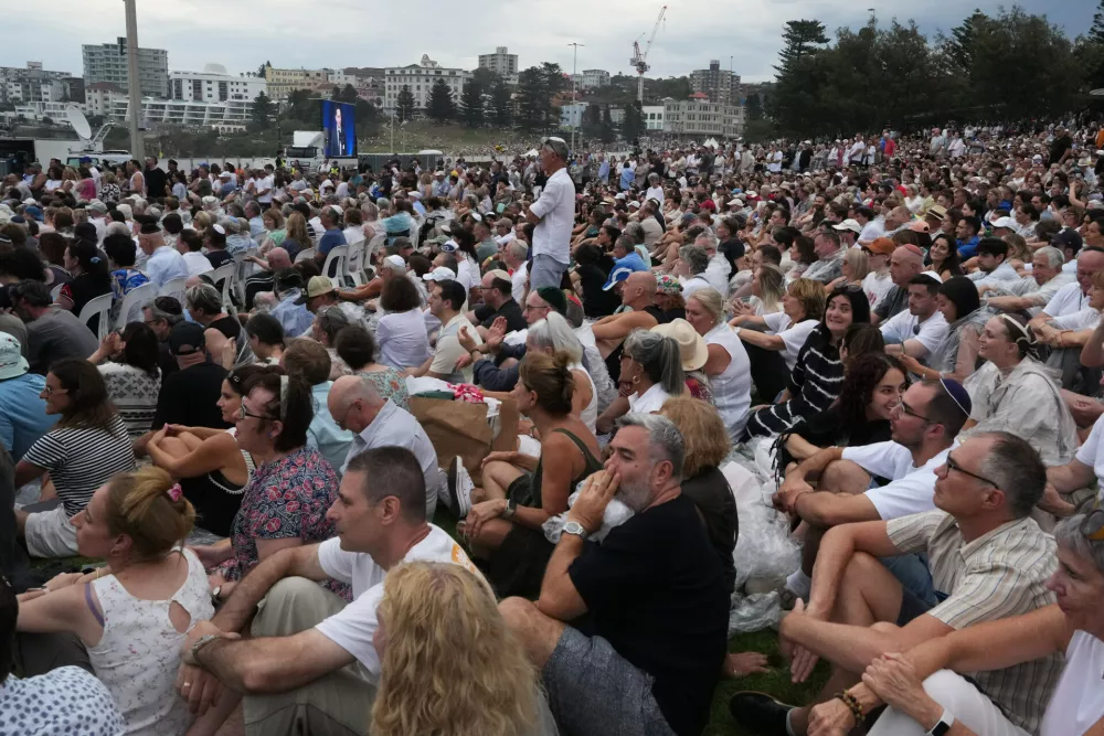 Attendees listen to David Ossip, president of the New South Wales Jewish Board of Deputies, during a ceremony to mark the National Day of Reflection for victims and survivors, at Bondi Beach in Sydney, Sunday, Dec. 21, 2025, following the Bondi shooting on Dec. 14. (AP Photo/Mark Baker)