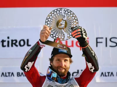 Alpine Skiing - FIS Alpine Ski World Cup - Men's Giant Slalom - Alta Badia, Italy - December 21, 2025 Austria's Marco Schwarz celebrates on the podium with a trophy after winning the men's giant slalom REUTERS/Angelika Warmuth