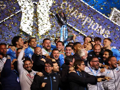 Soccer Football - Supercoppa Italiana - Final - Napoli v Bologna - Al Awwal Park, Riyadh, Saudi Arabia - December 23, 2025 Napoli players and staff celebrate on the podium as Giovanni Di Lorenzo lifts the Supercoppa Italiana trophy REUTERS/Guglielmo Mangiapane