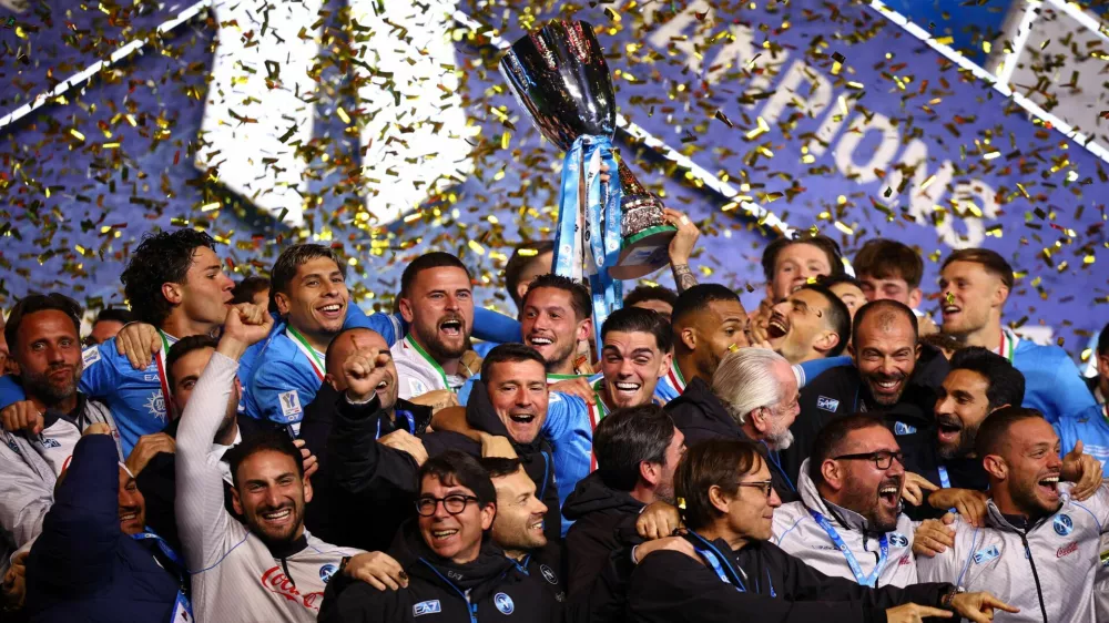 Soccer Football - Supercoppa Italiana - Final - Napoli v Bologna - Al Awwal Park, Riyadh, Saudi Arabia - December 23, 2025 Napoli players and staff celebrate on the podium as Giovanni Di Lorenzo lifts the Supercoppa Italiana trophy REUTERS/Guglielmo Mangiapane