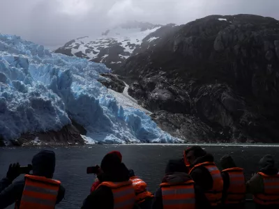 Tourists take photographs of the Sarmiento de Gamboa glacier in front of Santa Ines Island with their cell phones, during a boat trip in the Strait of Magellan, near the Brunswick Peninsula where Chile plans to create Cape Froward National Park to protect roughly 150,000 hectares of forests, peatlands, glaciers and coastline, in collaboration with Rewilding Chile, in Punta Arenas, Chile, December 2, 2025. REUTERS/Pablo Sanhueza