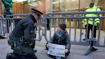In this photo, released by 'Prisoners for Palestine' on Tuesday, Dec. 23, 2025, climate activist Greta Thunberg, center, sits in front of offices of Aspen Insurance in London, England, during a protest to support the Palestine Action protesters on hunger strike in prison. (Prisoners for Palestine via AP)