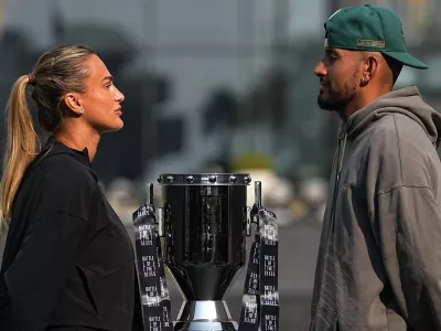 Tennis players Aryna Sabalenka of Belarus, left, and Nick Kyrgios of Australia face-off with the trophy during a press conference ahead of the Battle of the Sexes exhibition match at Atlantis The Royal in Dubai, United Arab Emirates, Saturday, Dec. 27, 2025. (AP Photo/ Fatima Shbair)