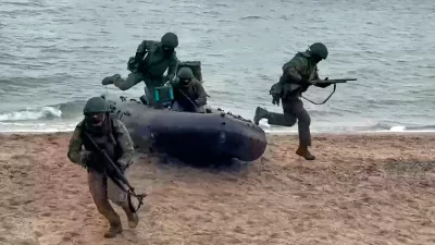 In this photo taken from video provided by Russian Defense Ministry Press Service on Thursday, Dec. 25, 2025, Russian soldiers leave a boat to set ensure reliable communications in an undisclosed location in Ukraine. (Russian Defense Ministry Press Service via AP)