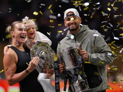 Aryna Sabalenka holds her goddaughter next to Nick Kyrgios as they pose with trophies after their Battle of the Sexes tennis match, in Dubai, United Arab Emirates, Sunday Dec. 28, 2025. (Amr Alfiky/Pool Photo via AP)