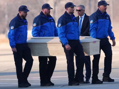Police officers carry a coffin with a body of one of six Italians at the Military Airport in Sion, Swiss Alps, Switzerland, Monday, Jan. 5, 2026, following a devastating fire left dead and injured in a bar in Crans-Montana during the New Year's celebrations. (AP Photo/Antonio Calanni)