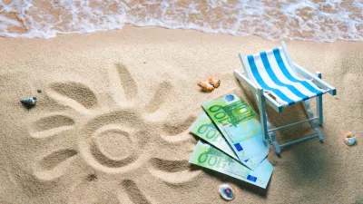 Deckchair with euro bills on a beach with a sun drawn on the sand. Travel money savings concept