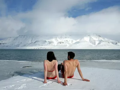 FILE PHOTO: Climate activists Lesley Butler and Rob Bell (R) "sunbathe" on the edge of a frozen fjord in the Norwegian Arctic town of Longyearbyen April 25, 2007. REUTERS/Francois Lenoir/File Photo