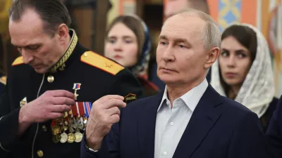Russian President Vladimir Putin, right, accompanied by military personnel and their families, crosses himself during the Orthodox Christmas service at the Church of Great-Martyr St. George the Victorious in Solnechnogorsk-2, outside Moscow, on Wednesday, Jan. 7, 2026. (Vyacheslav Prokofyev, Sputnik, Kremlin Pool Photo via AP)