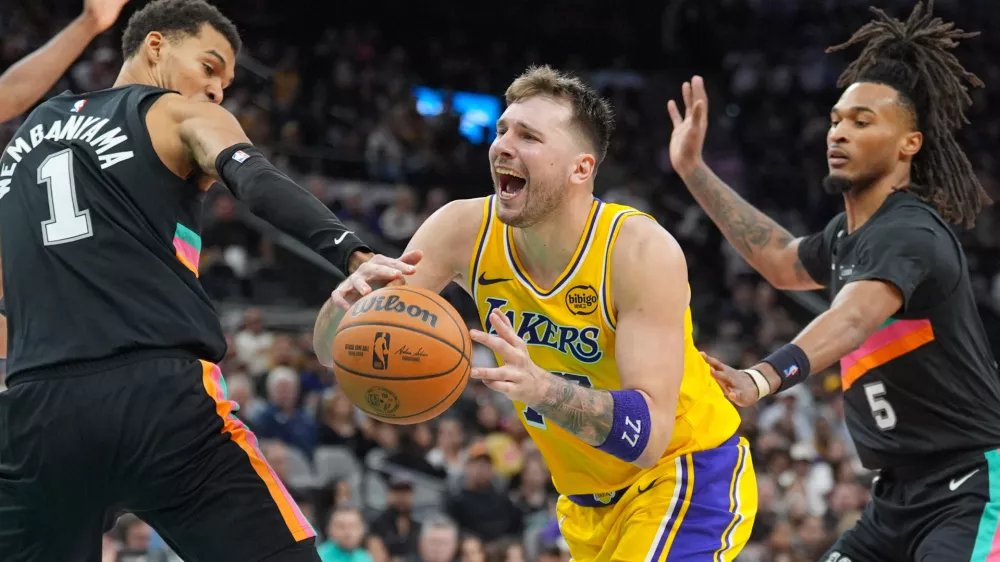 Jan 7, 2026; San Antonio, Texas, USA; Los Angeles Lakers forward/guard Luka Dončić (77) draws a foul in between San Antonio Spurs forward/center Victor Wembanyama (1) and guard Stephon Castle (5) in the second half at Frost Bank Center. Mandatory Credit: Daniel Dunn-Imagn Images