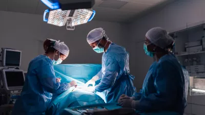 An intricate surgical procedure in progress with healthcare professionals in full surgical gear, under bright operating room lights, emphasizing the modern medical equipment and organization.