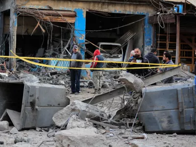 People check the site where an Israeli strike destroyed a building at a commercial district in the southern port city of Sidon, Lebanon, Tuesday, Jan. 6, 2026. (AP Photo/Mohammed Zaatari)