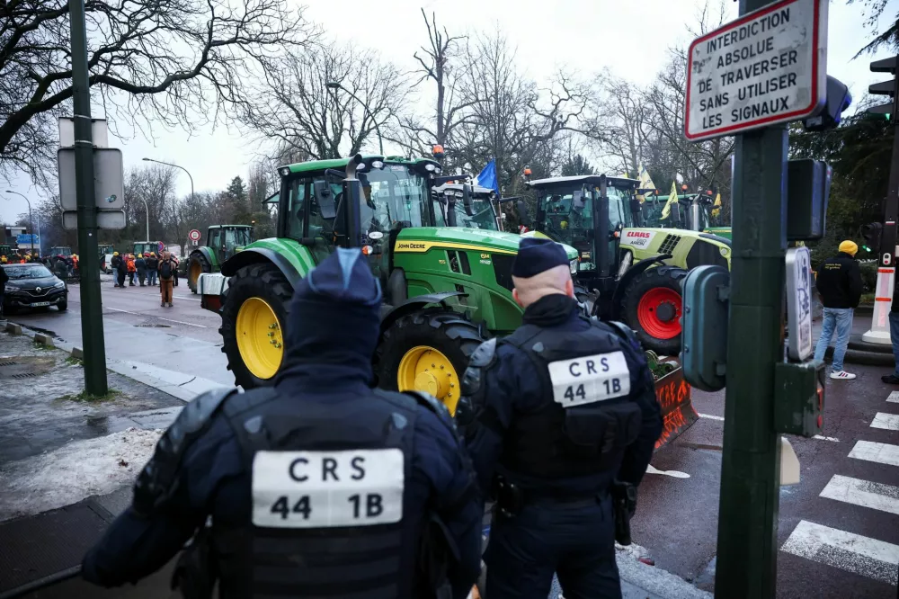 CRS Police officers stand next to tractors blocking a road at Porte d'Auteuil, as French farmers protest against the government's handling of the EU-Mercosur free trade agreement and the handling of the lumpy skin disease outbreak, in Paris, France January 8, 2026. REUTERS/Gonzalo Fuentes