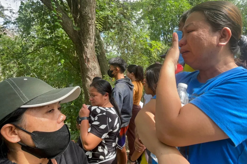 Relatives and others wait for updates after a huge mound of garbage collapsed at a waste segregation facility in Binaliw, Cebu city on Friday, Jan. 9, 2026. (AP Photo/Jacqueline Hernandez)