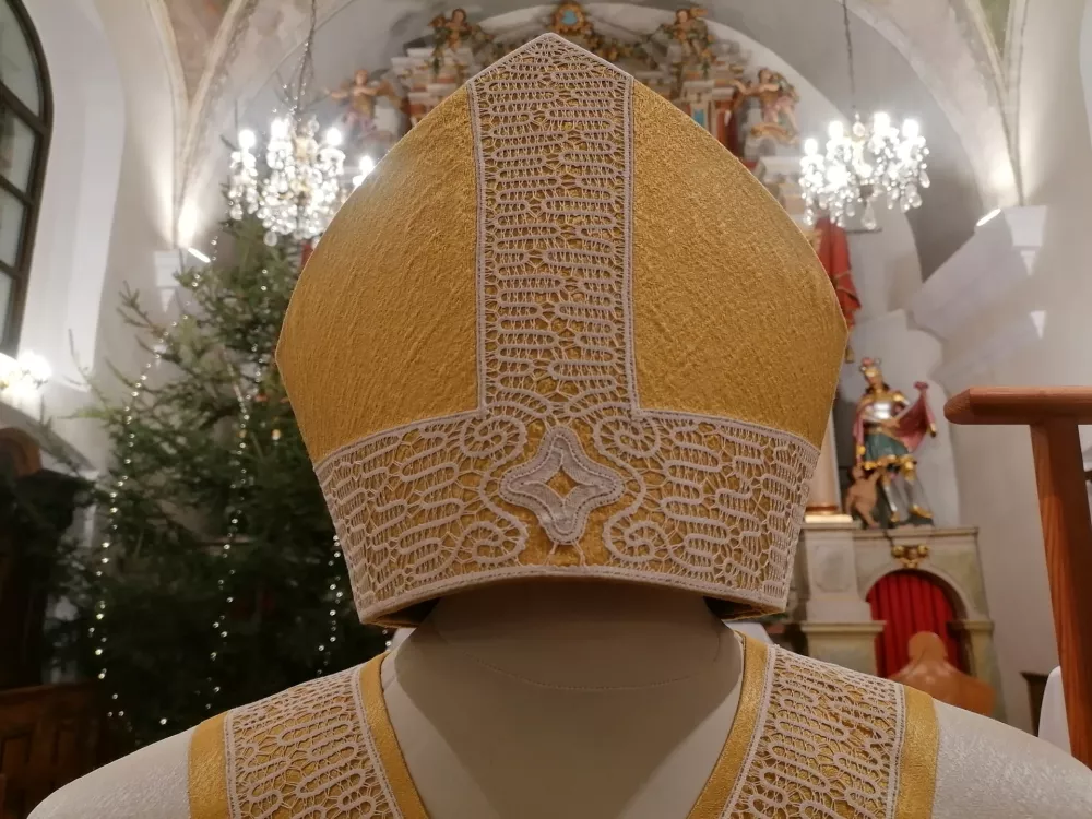 Spodnja Idrija, zupnijska cerkev.Predstavitev masnega plasca in mitre z idrijsko cipko kot darilo papezu.Motiv mitre z idrijsko cipko.