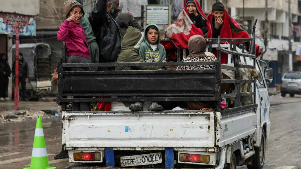People ride in the back of a vehicle in the Ashrafieh neighbourhood, after the Kurdish-led Syrian Democratic Forces (SDF) fighters left the Syrian city of Aleppo on Sunday, according to Ekhbariya TV, following a ceasefire deal that allowed evacuations after days of deadly clashes, in Aleppo, Syria, January 11, 2026. REUTERS/Khalil Ashawi