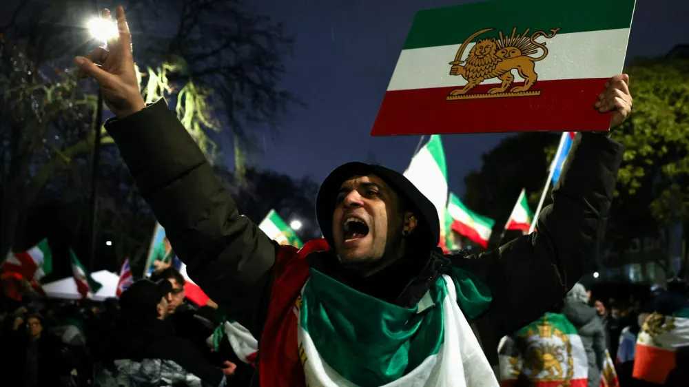 A man gestures while displaying the "Lion and Sun" pre-Iranian Revolution national flag as demonstrators gather outside the Iranian embassy during a rally in support of nationwide protests in Iran, in London, Britain, January 11, 2026. REUTERS/Isabel Infantes