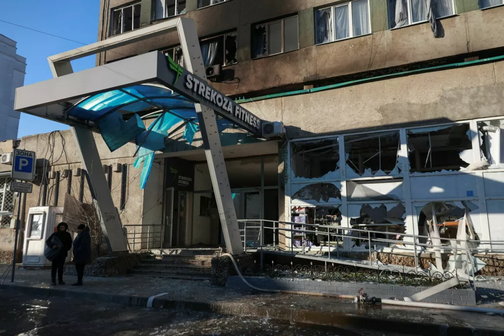 Residents stand next to a building of Professional Lyceum of Construction and Architecture hit by a Russian drone strike, amid Russia's attack on Ukraine, in Odesa, Ukraine January 13, 2026. REUTERS/Nina Liashonok
