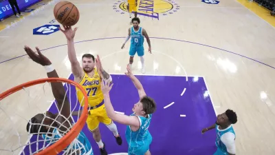 Jan 15, 2026; Los Angeles, California, USA; Los Angeles Lakers guard Luka Doncic (77) shoots the ball against Charlotte Hornets forward Moussa Diabate (14) and guard Kon Knueppel (7)] in the second half at Crypto.com Arena. Mandatory Credit: Kirby Lee-Imagn Images