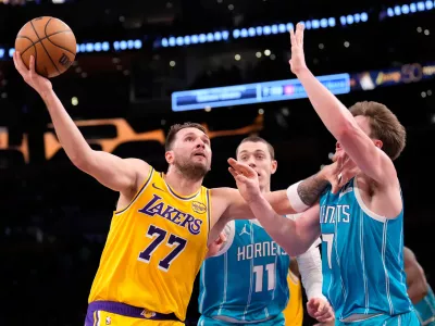 Los Angeles Lakers guard Luka Doncic, left, shoots as Charlotte Hornets center Ryan Kalkbrenner, center, and guard Kon Knueppel defend during the first half of an NBA basketball game Thursday, Jan. 15, 2026, in Los Angeles. (AP Photo/Mark J. Terrill)