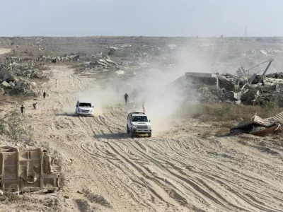 A Red Cross vehicle, escorted by a van driven by a Hamas militant, moves in an area within the so-called "yellow line" to which Israeli troops withdrew under the ceasefire, as Hamas says it continues to search for the bodies of deceased hostages seized during the October 7, 2023, attack on Israel, in Gaza City November 12, 2025. REUTERS/Dawoud Abu Alk
