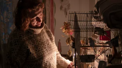 Tetyana Tatarenkova stands with a candle near a cage with ploughs during a power outage caused by regular Russian air strikes on the country's energy facilities in Kyiv, Ukraine, Tuesday, Jan. 13, 2026. (AP Photo/Dan Bashakov)