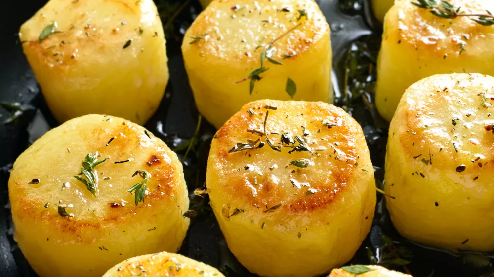 Fondant potatoes in frying pan over wooden table. Close up view / Foto: Tatiana Volgutova