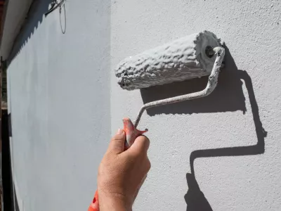 Painter's hand holding a roller filled with paint to paint an exterior wall / Foto: Leirao, Getty Images