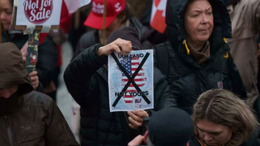A man holds a map of Greenland covered in the American flag crossed out with an X during a protest against Trump's policy towards Greenland in front of the US consulate in Nuuk, Greenland, Saturday, Jan. 17, 2026. (AP Photo/Evgeniy Maloletka)