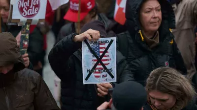 A man holds a map of Greenland covered in the American flag crossed out with an X during a protest against Trump's policy towards Greenland in front of the US consulate in Nuuk, Greenland, Saturday, Jan. 17, 2026. (AP Photo/Evgeniy Maloletka)