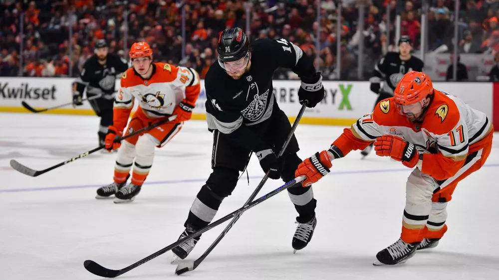 Jan 17, 2026; Anaheim, California, USA; Los Angeles Kings right wing Alex Laferriere (14) moves the puck against Anaheim Ducks left wing Alex Killorn (17) during the third period at Honda Center. Mandatory Credit: Gary A. Vasquez-Imagn Images