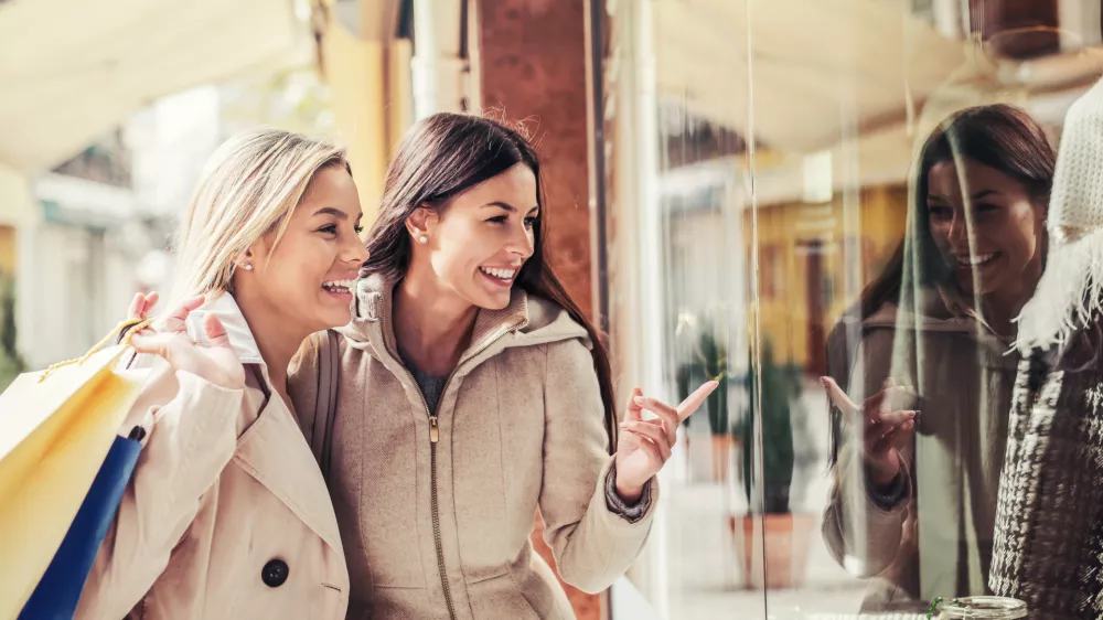 Women in shopping. Two happy women with shopping bags enjoying in shopping, having fun in the city. Consumerism, shopping, lifestyle concept