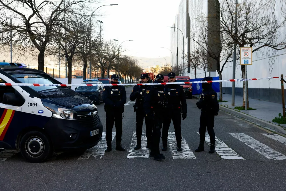 Spanish police officers stand behind a security cordon near the City of Justice building, which is being used as a morgue, following the deadly derailment of two high-speed trains near Adamuz, in Cordoba, Spain, January 20, 2026. REUTERS/Jon Nazca