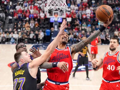 Los Angeles Clippers forward John Collins, center, shoots as Los Angeles Lakers guard Luka Doncic, left, defends during the first half of an NBA basketball game Thursday, Jan. 22, 2026, in Inglewood, Calif. (AP Photo/Mark J. Terrill)