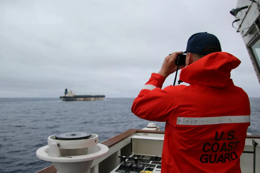 A U.S. Coast Guard official looks through binoculars at the ship Marinera (Ex-Bella 1) in this handout image released January 7, 2026. US EUROPEAN COMMAND via X/Handout via REUTERS  THIS IMAGE HAS BEEN SUPPLIED BY A THIRD PARTY. MANDATORY CREDIT. Verification lines: Reuters was not able to independently verify the location or the date when the photos were taken. But a U.S. official told Reuters the United States had pursued the tanker for more than two weeks across the Atlantic. Searches for the images found they had not appeared online before. The identity of the oil tanker was confirmed by the structures on the deck and bridge which matched file imagery.