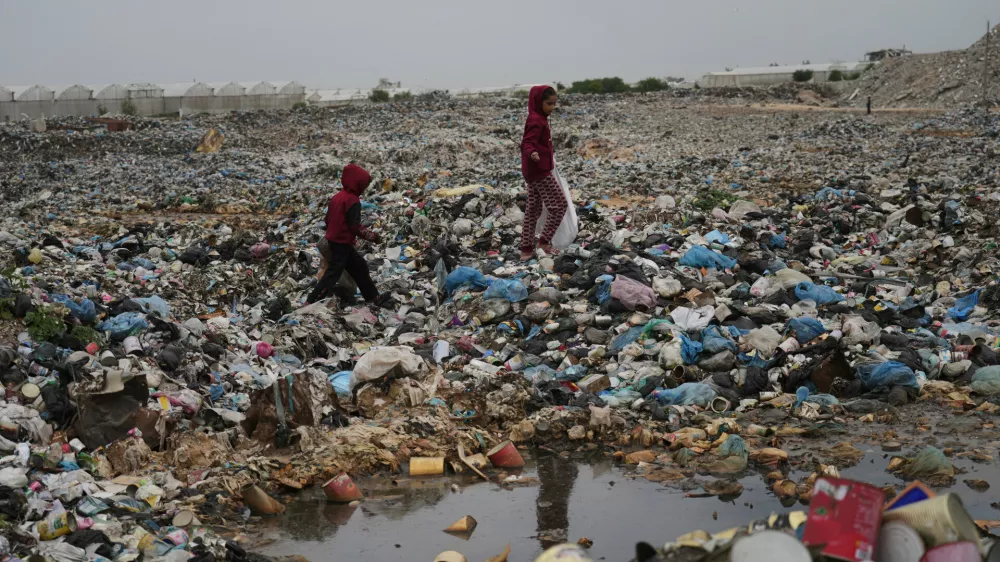 Palestinian girls Jana Al-Basouni and Lina Hamdin collect plastic and paper to burn for cooking and warmth, at a landfill in Khan Younis, Gaza, Thursday, Jan. 22, 2026. (AP Photo/Jehad Alshrafi)