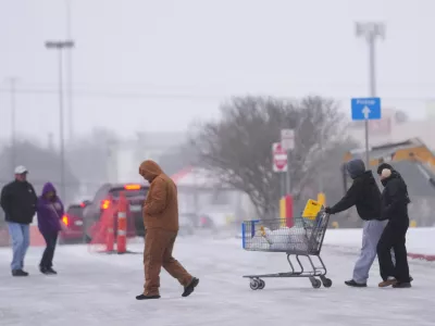 Shoppers brave cold weather as they walk in the parking lot of a store during a winter storm Saturday, Jan. 24, 2026, in Arlington, Texas. (AP Photo/Julio Cortez)