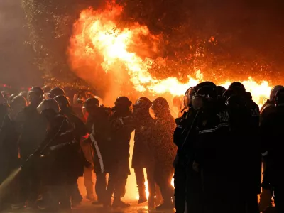 Law enforcement officers stand guard as other officers extinguish a fire outside the Prime Minister's office during an anti-government protest triggered by a corruption investigation into Deputy Prime Minister Belinda Balluku, in Tirana, Albania, January 24, 2026. REUTERS/Florion Goga