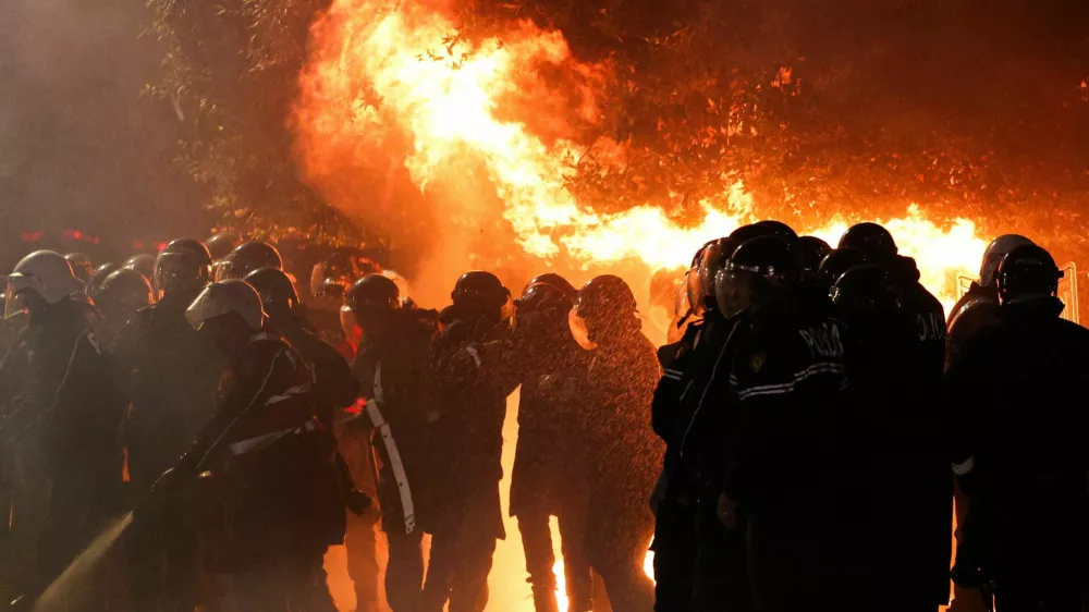 Law enforcement officers stand guard as other officers extinguish a fire outside the Prime Minister's office during an anti-government protest triggered by a corruption investigation into Deputy Prime Minister Belinda Balluku, in Tirana, Albania, January 24, 2026. REUTERS/Florion Goga
