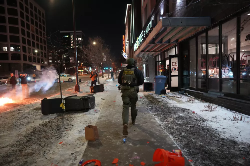 Federal agents run in to clear a hotel during a noise demonstration protest in response to federal immigration enforcement operations in the city Sunday, Jan. 25, 2026, in Minneapolis. (AP Photo/Adam Gray)