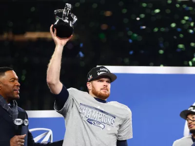 Jan 25, 2026; Seattle, WA, USA; Seattle Seahawks quarterback Sam Darnold (14) celebrates with the trophy on the podium after defeating the Los Angeles Rams in the 2026 NFC Championship Game at Lumen Field. Mandatory Credit: Kevin Ng-Imagn Images