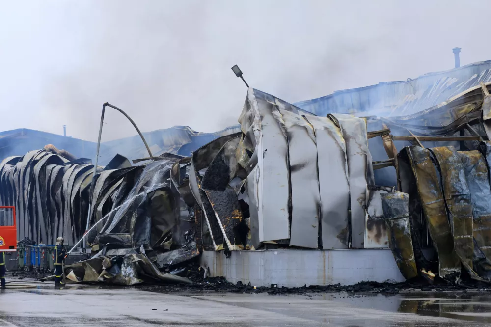 A firefighter sprays water after an explosion and fire at a cookie factory in Trikala, central Greece, on Monday, Jan. 26, 2026. (George Kidonas/InTime News via AP)