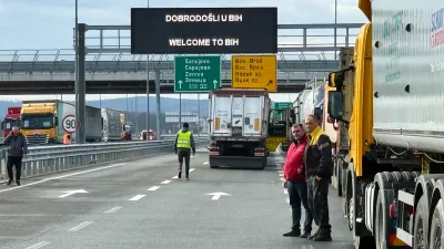 Men stand next to a line of trucks and buses on the Bosnian side of the border with Croatia, in Svilaj, Bosnia, Monday, Jan. 26, 2026, as drivers across the Balkans blocked dozens of border crossings in the region in protest over newly introduced European Union entry regulations.(AP Photo/Eldar Emric)