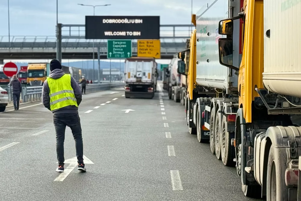 A man stands next to a line of trucks and buses on the Bosnian side of the border with Croatia, in Svilaj, Bosnia, Monday, Jan. 26, 2026, as drivers across the Balkans blocked dozens of border crossings in the region in protest over newly introduced European Union entry regulations.(AP Photo/Eldar Emric)