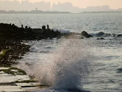 Waves crash against the rocks near where people sit on the shore of the Mediterranean Sea, in the port city of Alexandria, Egypt, January 25, 2026. REUTERS/Mohamed Abd El Ghany