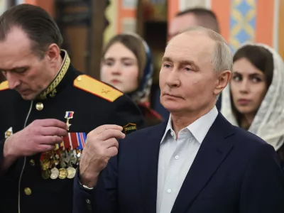 Russian President Vladimir Putin, right, accompanied by military personnel and their families, crosses himself during the Orthodox Christmas service at the Church of Great-Martyr St. George the Victorious in Solnechnogorsk-2, outside Moscow, on Wednesday, Jan. 7, 2026. (Vyacheslav Prokofyev, Sputnik, Kremlin Pool Photo via AP)