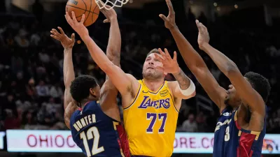 Los Angeles Lakers guard Luka Doncic shoots between Cleveland Cavaliers forward De'andre Hunter (12) and center Thomas Bryant (3) in the second half of an NBA basketball game in Cleveland, Wednesday, Jan. 28, 2026. (AP Photo/Sue Ogrocki)